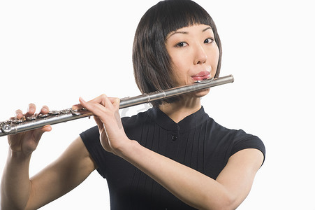 演奏摄影照片_一位女性长笛演奏家在白色背景下演奏长笛的肖像
