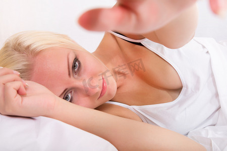 侧躺摄影照片_金发女孩躺在床上伸手去拿东西