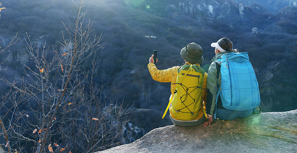 彩色岩石摄影照片_青年登山者伴侣坐在岩石上自拍
