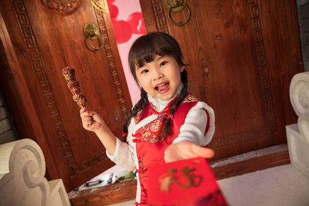 开着大门摄影照片_吃糖葫芦的快乐小女孩