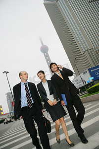 中外交流摄影照片_东方明珠电视塔下三位中外商务人士行走交谈