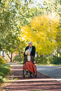 老年男人推着坐轮椅的老伴散步