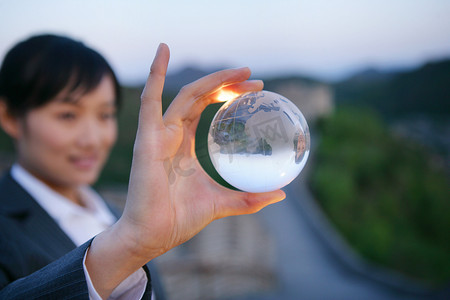 女商务人士在长城上展示水晶地球