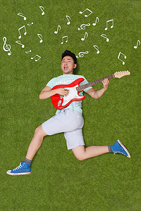 年轻男子躺在草地上弹吉他