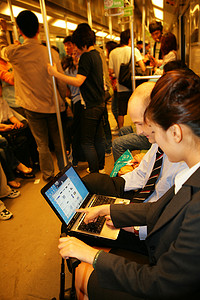 上海地铁车厢内三位中外商务人士拿笔记本电脑交谈