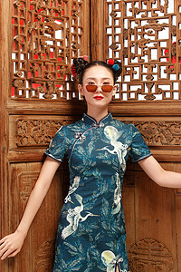 花纹旗袍摄影照片_站在中式门前的漂亮女人