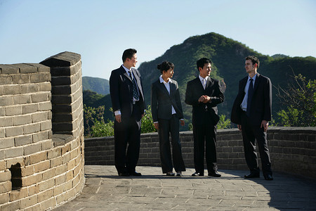 四位中外商务人士在长城上站立交谈