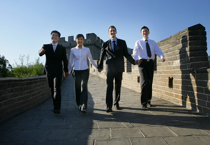 四位中外商务人士在长城上牵手行走