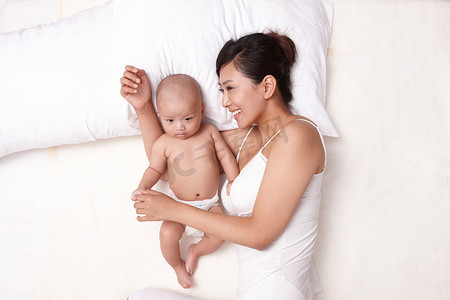母子沟通摄影照片_母亲和婴儿躺在床上休息