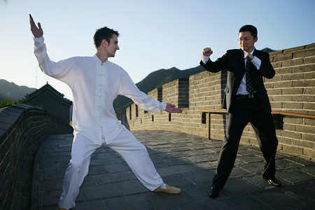穿中式传统服装的外国人和中国商务人士在长城上比武