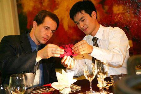 传统剪纸摄影照片_中外商务人士坐在酒店餐桌旁欣赏剪纸