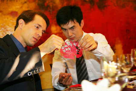 中外商务人士坐在酒店餐桌旁欣赏剪纸