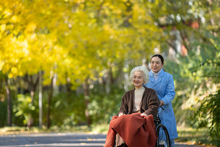 医药摄影照片_护士推着坐在轮椅上的老人散步