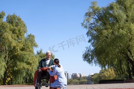轮椅治疗摄影照片_护士照看坐在轮椅上的老年人