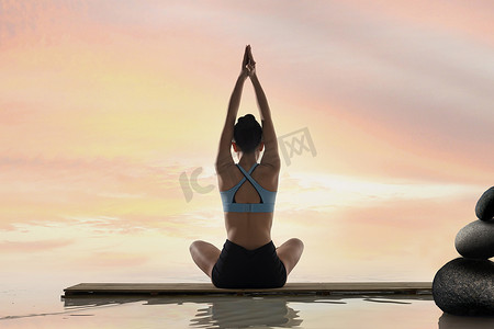 瑜伽垫文字排版摄影照片_年轻女人在水面上练习瑜伽
