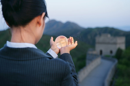 女商务人士在长城上手捧水晶地球