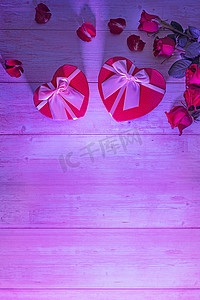 心形盒子，情人的礼物，木制表面，霓虹灯紫色的强光，玫瑰，花瓣。情人节2月14日或浪漫的夜晚邀请函、明信片、海报、装饰品