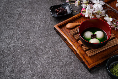 Close up of matcha big tangyuan (tang yuan) with sweet matcha soup in a bowl on wooden table background for festival food.