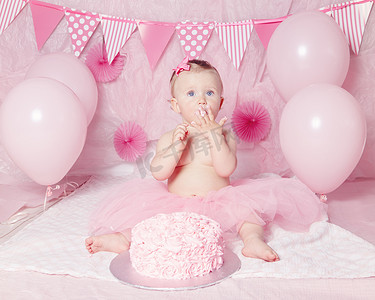 蓝色可爱可爱高加索女婴的肖像在庆祝她第一次与美食蛋糕生日的粉色芭蕾短裙的眼睛和气球看去，蛋糕粉碎第一年概念