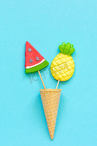 明信片模板摄影照片_菠萝和西瓜棒棒糖在冰淇淋华夫饼锥在蓝纸背景。概念你好夏季，假期或假期创意顶视图模板贺卡，明信片