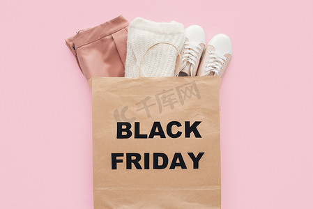 最热门的时尚服装在购物袋与黑色星期五标志被隔离粉红色 