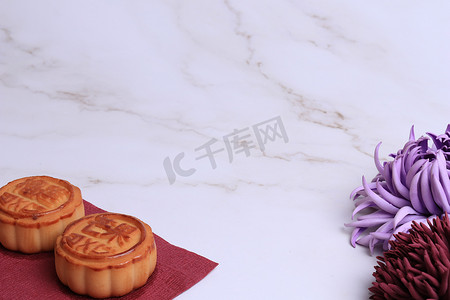 白色大理石背景上的中国月饼和菊花是秋天的象征。亚洲传统的中秋节。象形文字的翻译：芒果、石榴和荷花