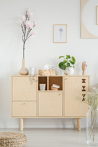 鲜花海报摄影照片_木制橱柜与鲜花在白色的房间内与海报和脚凳。真实照片