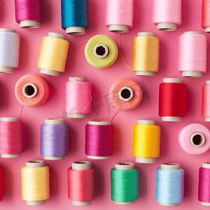 纺织业彩色丝线筒排列在粉色背景上2