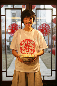中国年轻女人手端一碗水饺
