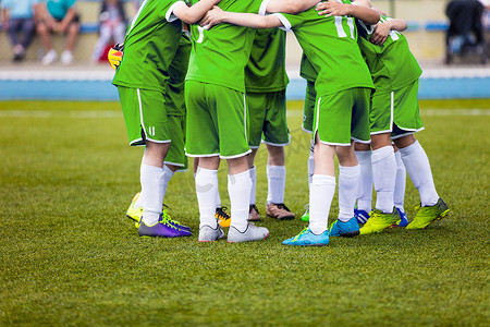 绿色运动服的年轻足球足球运动员。年轻的运动队，在球场上。在最后一场比赛前的动员讲话。足球学校锦标赛。孩子们在运动场上.