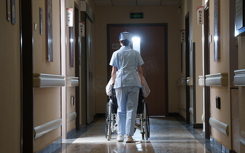 走廊内护士推坐轮椅的老人背影