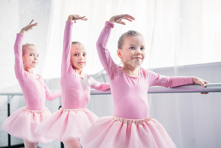 可爱的微笑的孩子粉红色的短裙裙舞在芭蕾工作室 