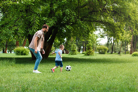 父亲和儿子在公园踢足球的侧面视图
