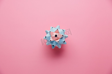 彩色手工制作的组合式折纸球或带粉色背景的熊达玛球。视觉艺术,几何,折纸艺术,造纸工艺.顶部视图，关闭，选择焦点，复制空间.