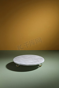 浅色背景的绿色桌子上的空灰色大理石盘
