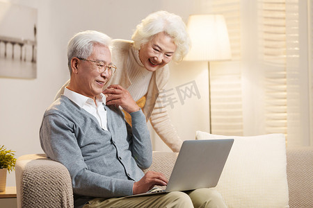老年沙发摄影照片_老年夫妇使用笔记本电脑