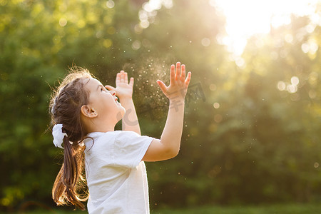 奔跑的孩子摄影照片_无忧无虑的孩子奔跑和跳跃在绿色夏天草甸捉住肥皂气泡。幸福、童年和自由概念
