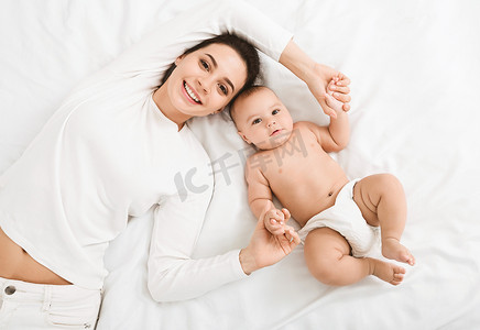 快乐的母亲和婴儿躺在床上的顶视图