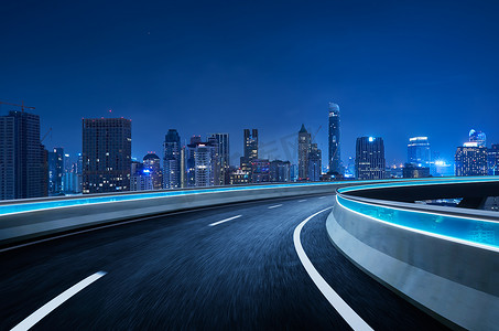 弯曲摄影照片_弯曲的天桥高速公路前进的道路与曼谷城市景观夜景。运动模糊效果适用