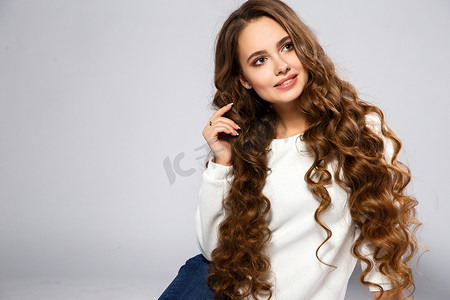 close摄影照片_Close-up portrait of beautiful young woman with gorgeous hair and natural makeup wearing casual clothes. Fashion beauty photo, casual jeans style