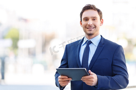 Grinning gentleman on balcony holding a tablet.