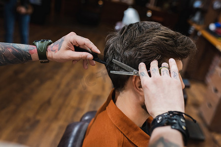 刺绣理发师用薄薄的剪刀剪头发的黑发男人