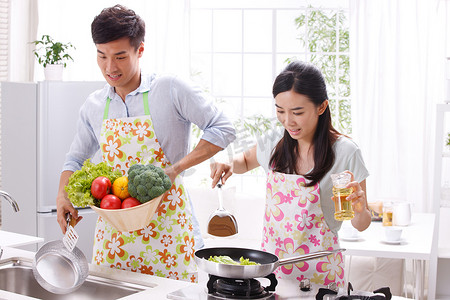 蔬菜清洗摄影照片_年轻夫妇在厨房做饭