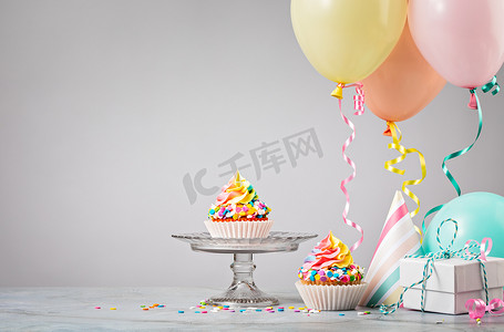 五彩缤纷水果茶摄影照片_五彩缤纷的气球派对上的彩虹生日蛋糕