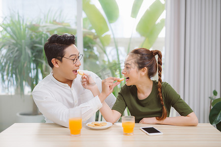 美满幸福的男男女女坐在餐桌旁，在家里吃早餐 