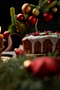 黑色覆盆子摄影照片_传统圣诞蛋糕的精选焦点，在圣诞花环附近的覆盆子放在木制桌子上，与黑色隔离