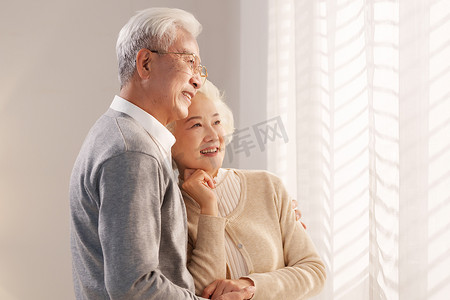 窗前摄影照片_幸福的老年夫妇站在窗前