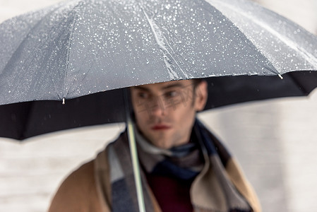 穿着外套和围巾的帅哥, 带着雨伞站在大街上