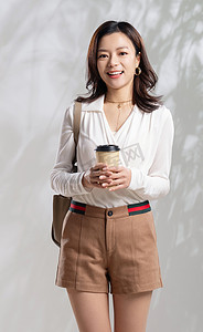 愉悦上班族摄影照片_拿着咖啡的年轻职业女性