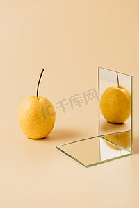 米色桌上两镜反射的有机黄梨